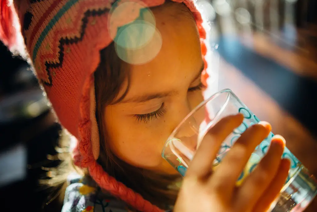 Liten flicka som dricker ur ett vattenglas.